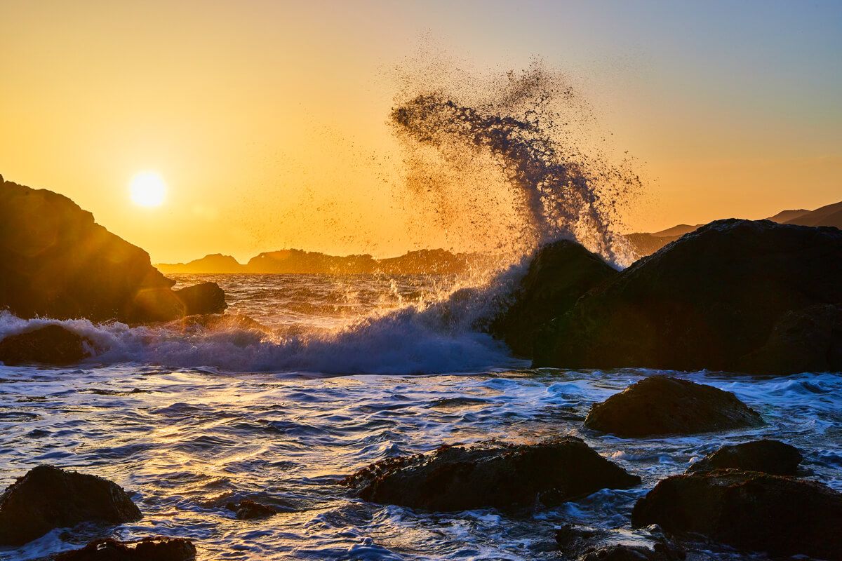 Beautiful waves crashing into rocks at sunset