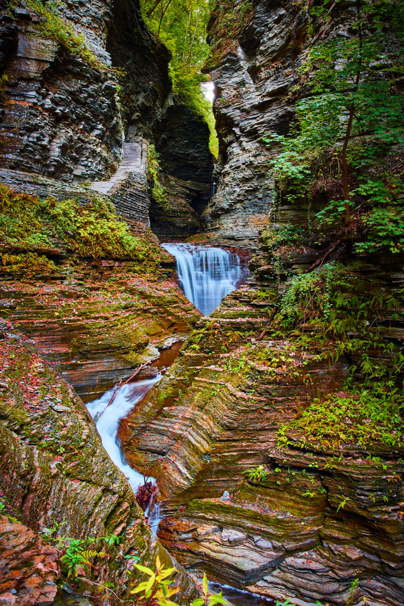 Layers of rock covered in fall leaves lead to this waterfall